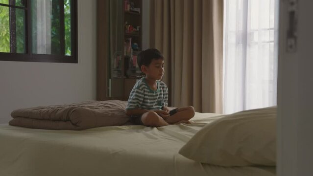 Asian boy practicing meditation in bedroom at home.	