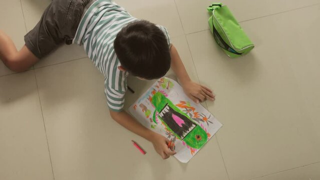 Top view of Cute Asian boy have fun Lie down on the floor drawing and paint 