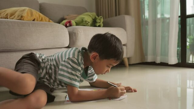 Cute Asian boy have fun Lie down on the floor drawing and paint 