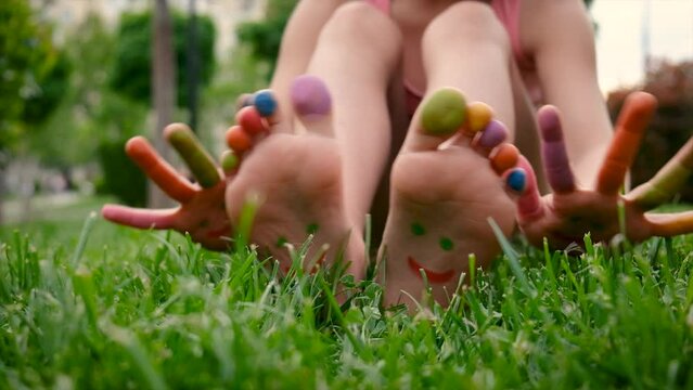 Child on the grass feet paint drawing. Selective focus.