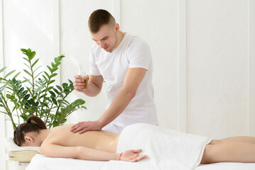 Young pretty woman having back massage in spa, white background. Copy space, closeup