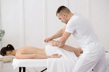 Young pretty woman having foot massage in spa, white background. Copy space, closeup