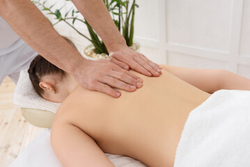 Fototapeta na wymiar Young pretty woman having back massage in spa, white background. Copy space, closeup