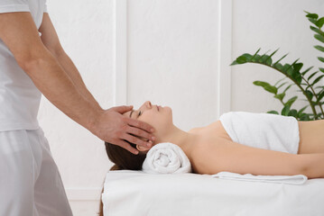 Young pretty woman having head massage in spa, white background. Copy space, closeup