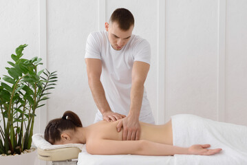 Young pretty woman having back massage in spa, white background. Copy space, closeup