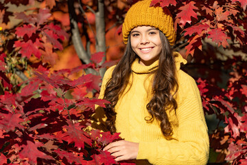 smiling teen kid in hat at autumn leaves on natural background