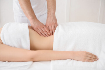 Close up of osteopath doing manipulative massage on woman abdomen on white background, copy space