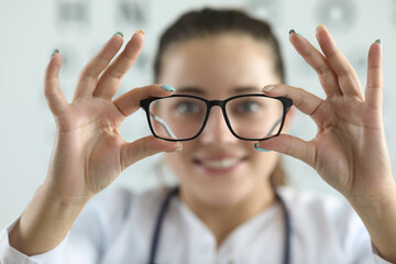 Female ophthalmologist doctor holding glasses in ophthalmology clinic - obrazy, fototapety, plakaty