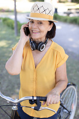 senior woman pushing bicycle and using smart phone