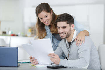 smiling couple using laptop taking care of utility bills