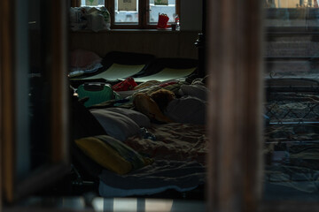 Fototapeta na wymiar Evening natural light through a window illuminates makeshift beds at a Ukrainian refugee camp in Krakow, Poland. Temporary shelter for Ukrainian women and children fleeing the war in Ukraine.