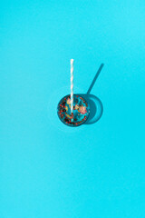 Drink in glass with dried herbs seasoning, flowers and paper straw on blue background. Time for drink concept.