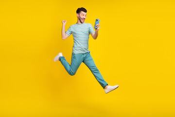 Fototapeta na wymiar Full size body photo of young funny guy jump air run take his prize bet online money phone isolated on yellow color background