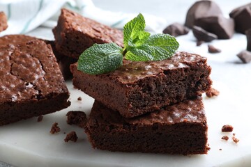 Delicious chocolate brownies with fresh mint on marble board, closeup