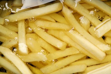 Cooking delicious french fries in hot oil, closeup