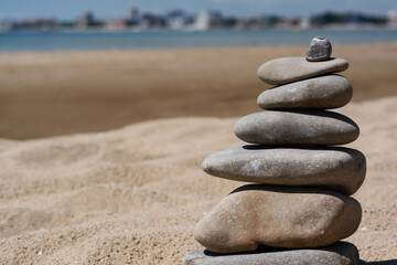Fototapeta na wymiar Stack of stones on beautiful sandy beach near sea, closeup. Space for text