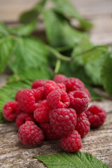 Fresh ripe raspberries and green leaves on wooden table, closeup