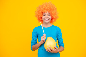 Happy teenager portrait. Funny child girl in wig hold big citrus fruit pummelo or pomelo full of...