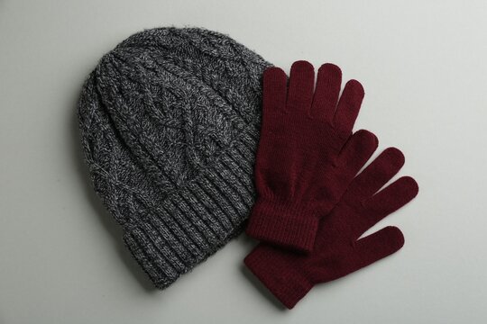 Woolen gloves and hat on light grey background, flat lay