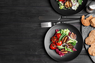 Delicious salad with roasted eggplant and basil served on black wooden table, flat lay. Space for text