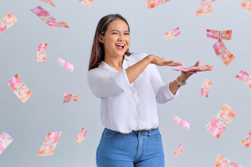 Cheerful young Asian woman throwing money banknotes isolated over white background