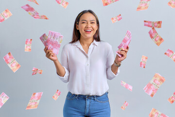 Cheerful young Asian woman holding money banknotes isolated over white background