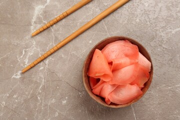 Spicy pickled ginger and chopsticks on grey table, flat lay
