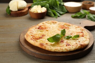 Delicious khachapuri with cheese and basil on wooden table