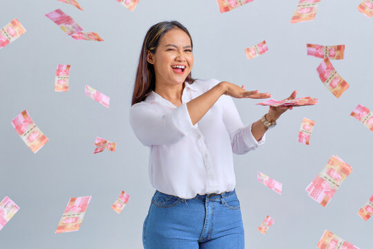 Cheerful Young Asian Woman Throwing Money Banknotes Isolated Over White Background