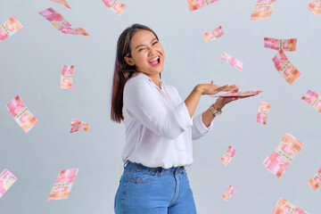 Cheerful young Asian woman throwing money banknotes isolated over white background