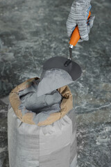 Man with cement powder near bag on stone floor