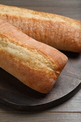 Tasty baguettes on wooden table, closeup. Fresh bread