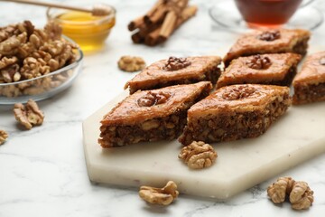 Delicious honey baklava with walnuts on served white marble table, closeup