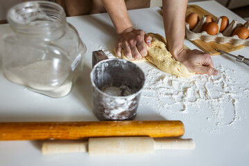 A woman in a special apron cooks at home. Rolling out and preparing dough for baking.
