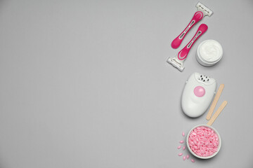 Modern epilator and other hair removal products on light grey background. Space for text