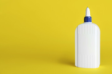 Bottle of glue on yellow background, space for text