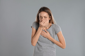 Woman suffering from nausea on grey background. Food poisoning