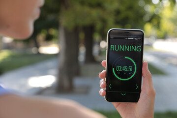 Young woman using fitness app on smartphone outdoors, closeup