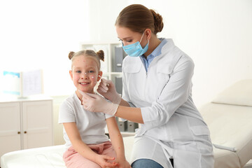 Doctor applying cream onto skin of little girl with chickenpox in clinic. Varicella zoster virus