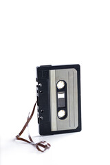 Musical audio cassette with tape stretched out sideways on a white background.