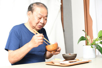 屋内で食事をする高齢者のアジア人男性