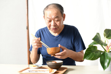 屋内で食事をする高齢者のアジア人男性