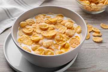 Tasty cornflakes with milk in bowl on wooden table, closeup