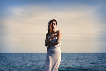Fototapeta na wymiar Sensual young female standing on seashore with closed eyes