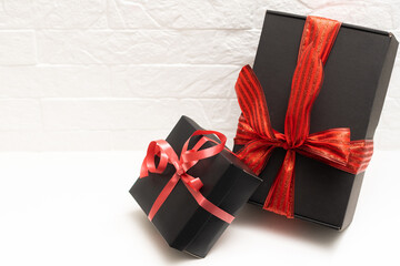 Black gift box with red bow and ribbons on a white background