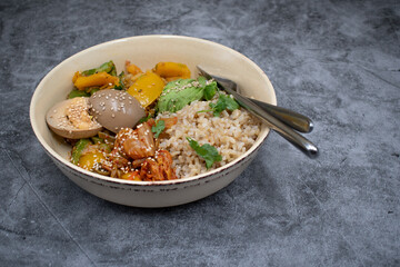 Korean brown rice, kimchi, stir fried vegetables and pickled egg, avocado in a bowl, copy space