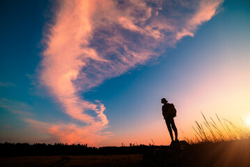 Girl hiker silhouette against majestic pink clouds