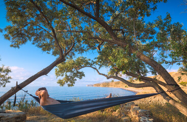 Man in a hammock under the tees on a beach