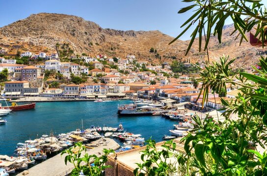A panoramic view of the the Greek Island, Hydra in Saronic gulf. The harbor, yachts and fishing boats docked at the seafront on a summer day.