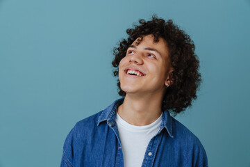 Curly young man wearing shirt smiling and looking aside